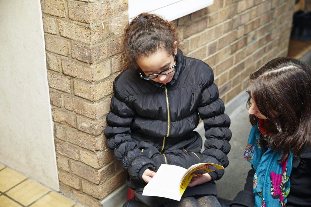 child-reading-book-on-doorstep