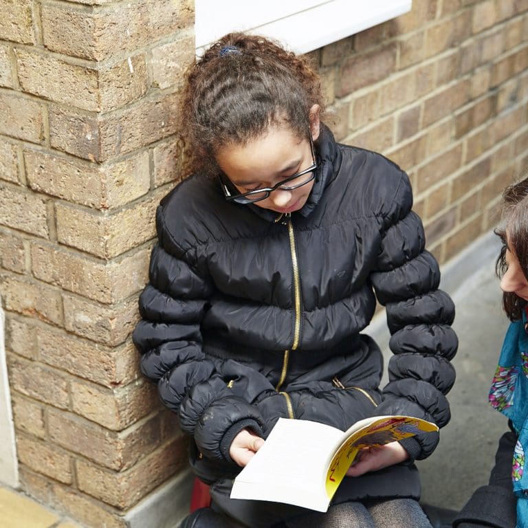 child-reading-book-on-doorstep