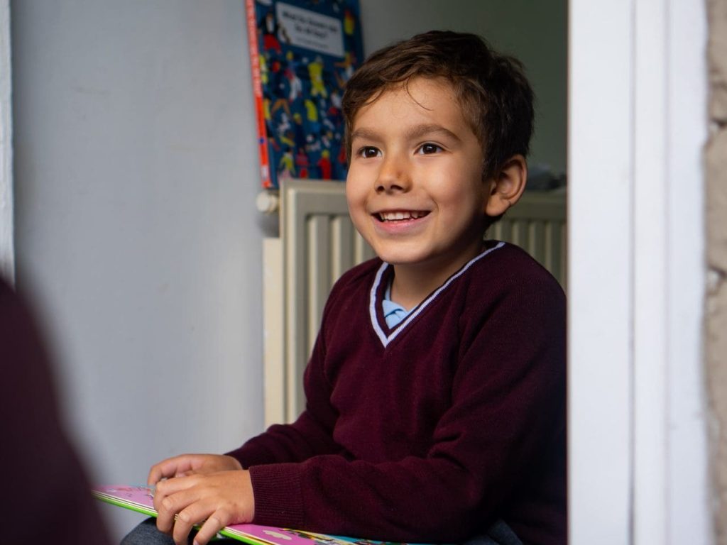 child-smiling-with-book-doorstep